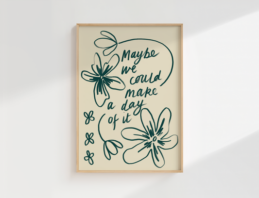 Framed artwork with the handwritten quote ‘maybe we could make a day of it’  with loose hand drawn flowers, set against a white wall.