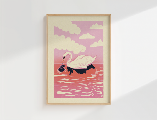 Framed artwork of a swan on water with a pink sky and clouds, displayed on a white wall.