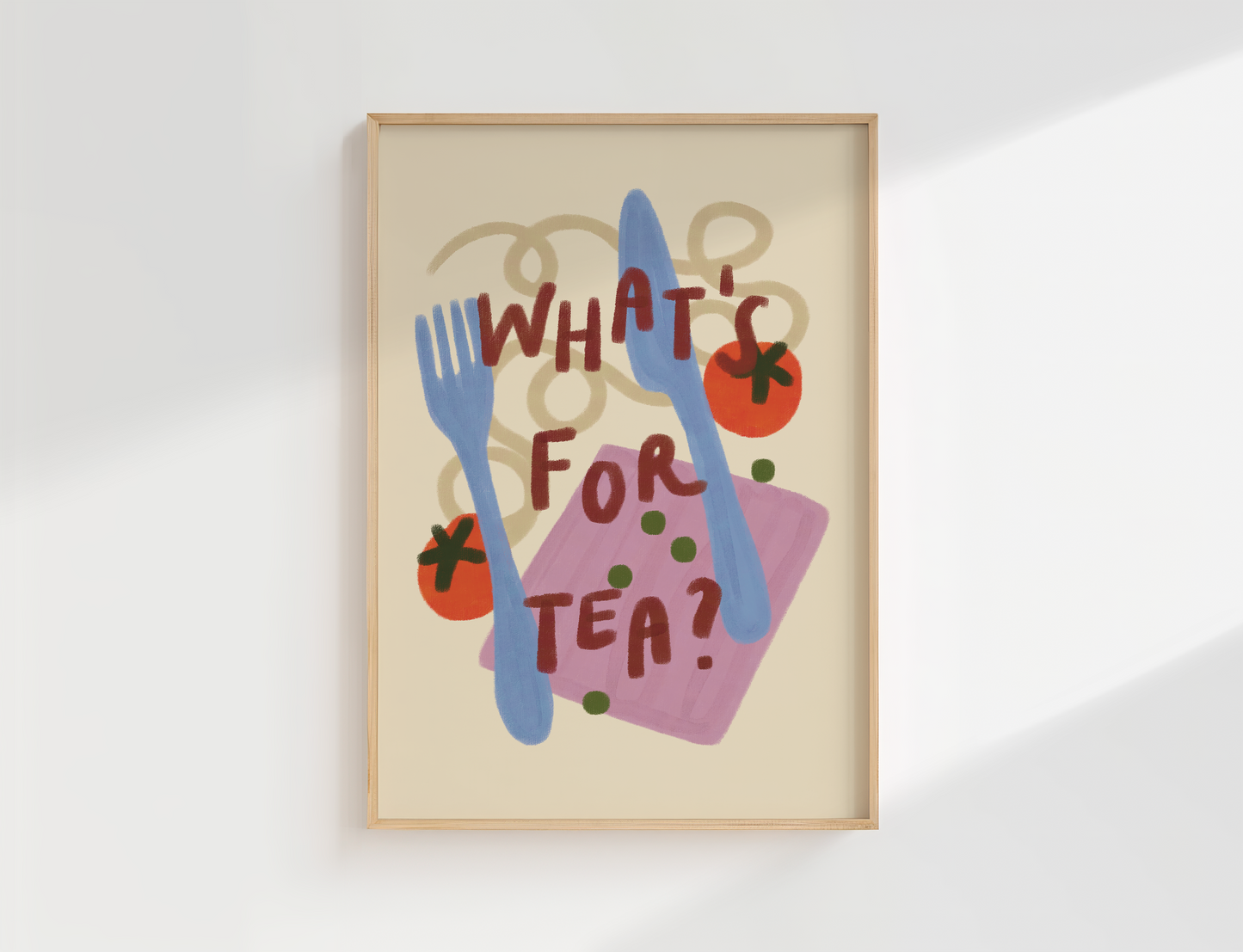 A framed art print featuring a whimsical illustration of a pink napkin, blue cutlery, red tomatoes, and green peas with the text 'WHAT'S FOR TEA?' on a cream background, displayed in a light wood frame against a white wall.