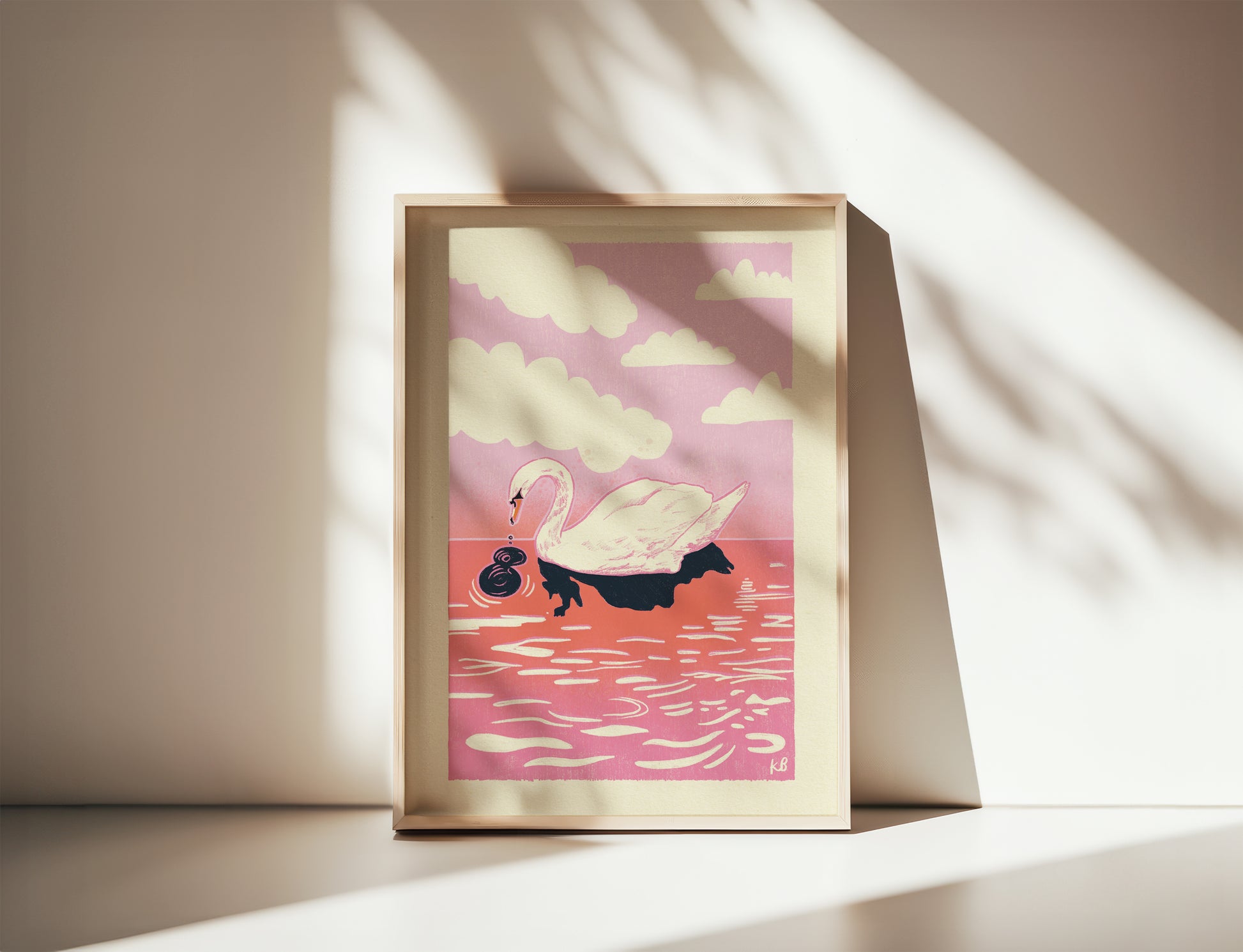 Framed artwork of a swan on water with a pink sky, placed on a light surface.